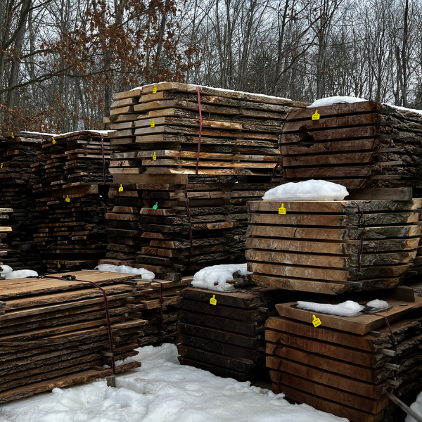Stack of black walnut slabs in a lumber yard.